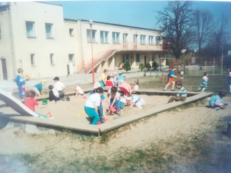 Dzieci bawiące się w piaskownicy w tle budynek przedszkola - stare zdjęcie